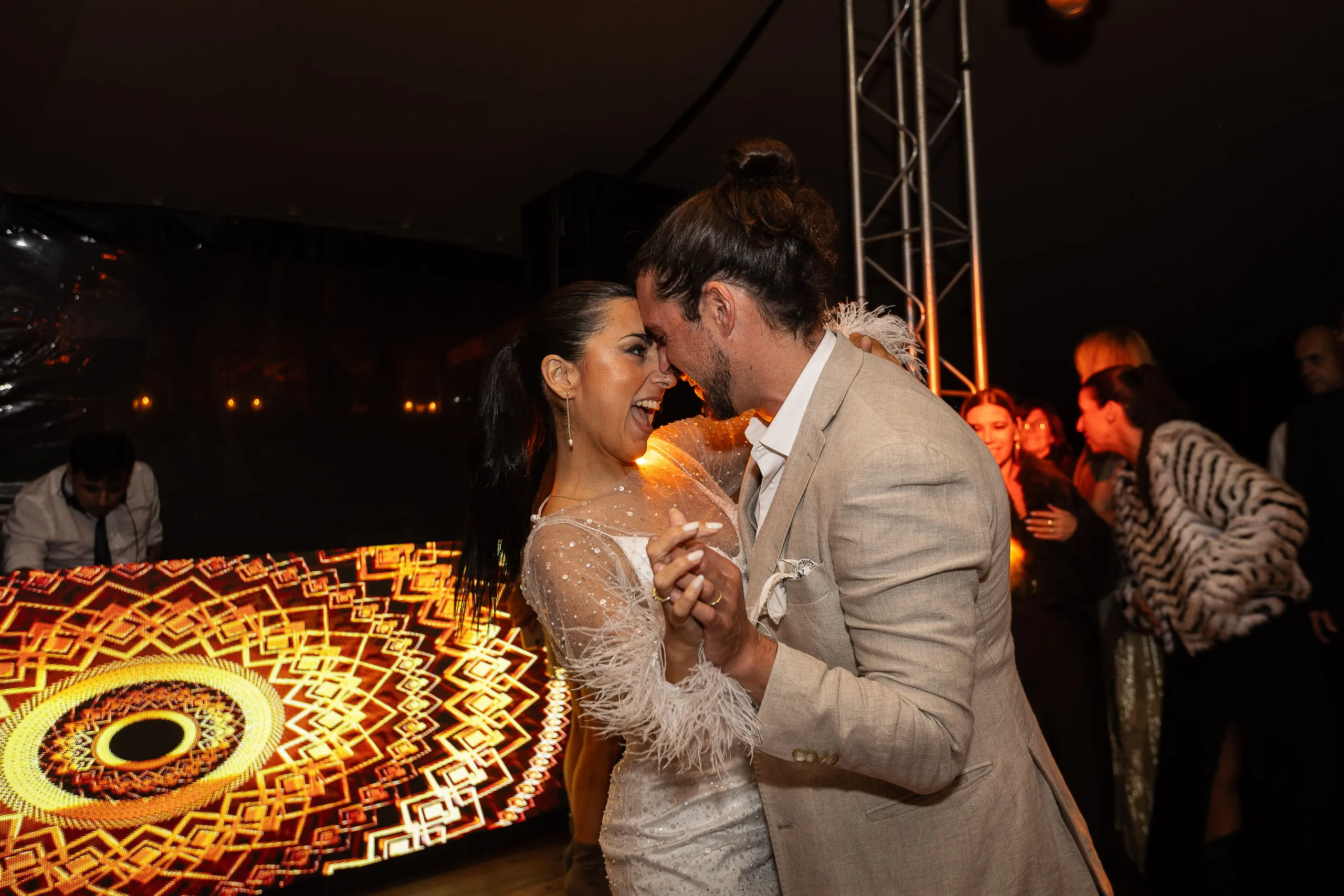 Los novios bailando de noche junto a una rueda de fuego encendida