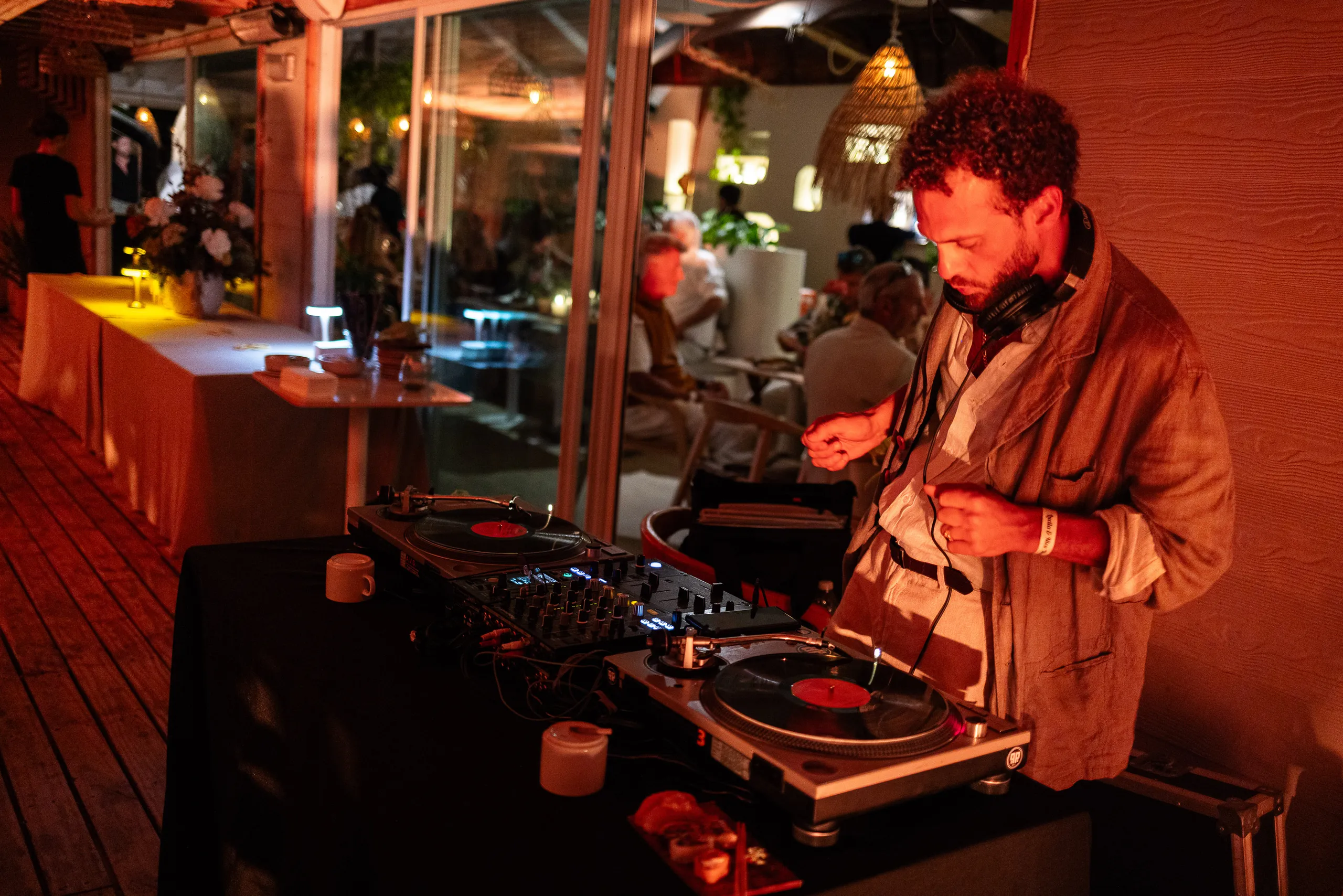 El DJ mezclando en bandejas de vinilo, con luz roja sobre el deck