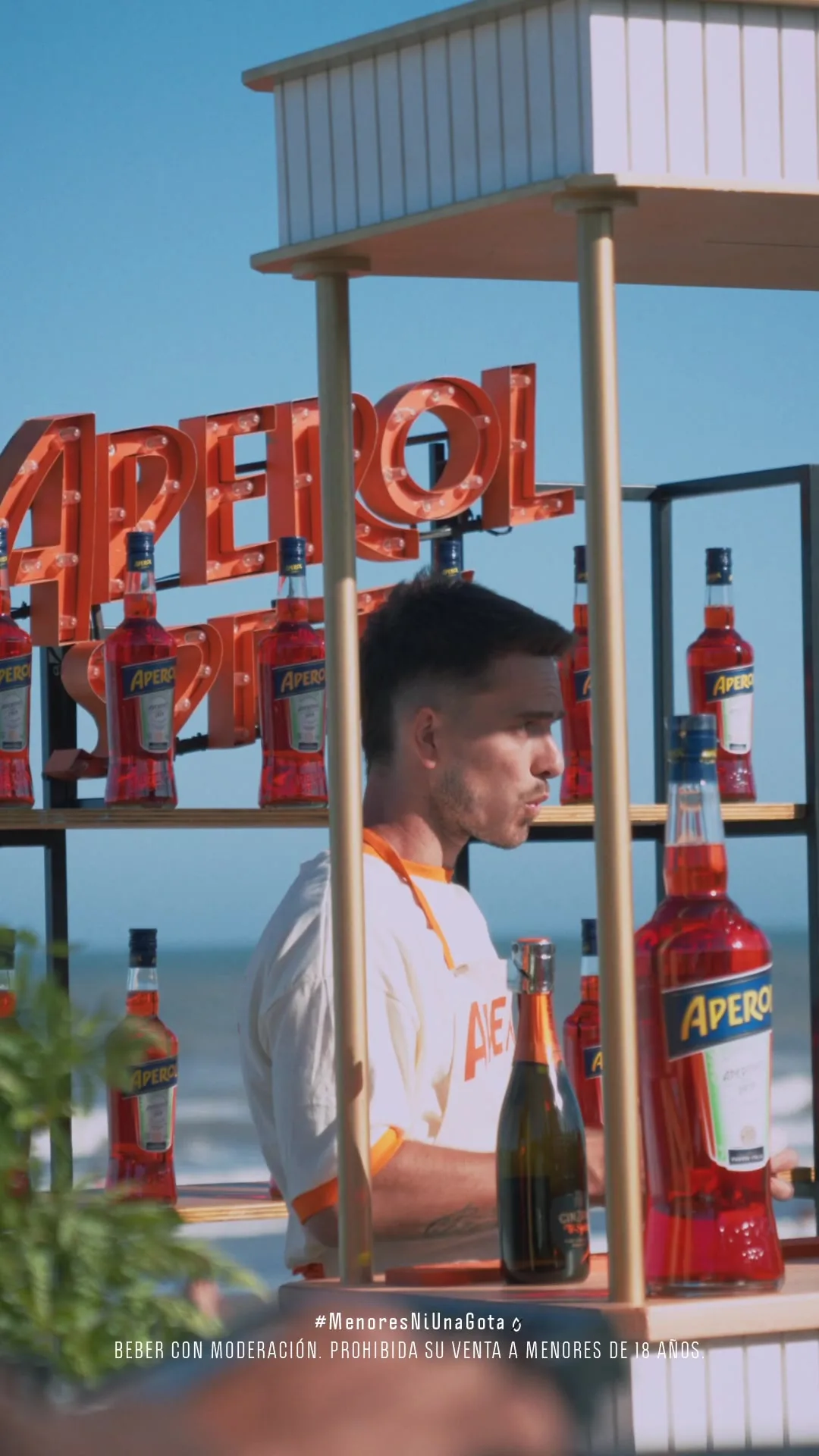 Barra de Aperol Spritz montada sobre el deck, con la cartelería de la marca y el mar de fondo