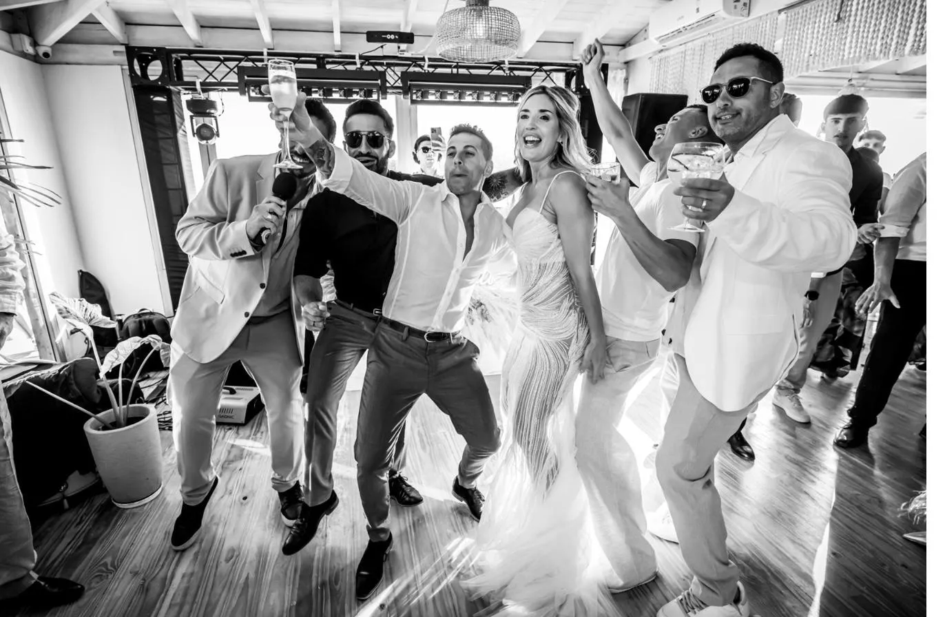 Los novios bailando rodeados por los invitados, en blanco y negro