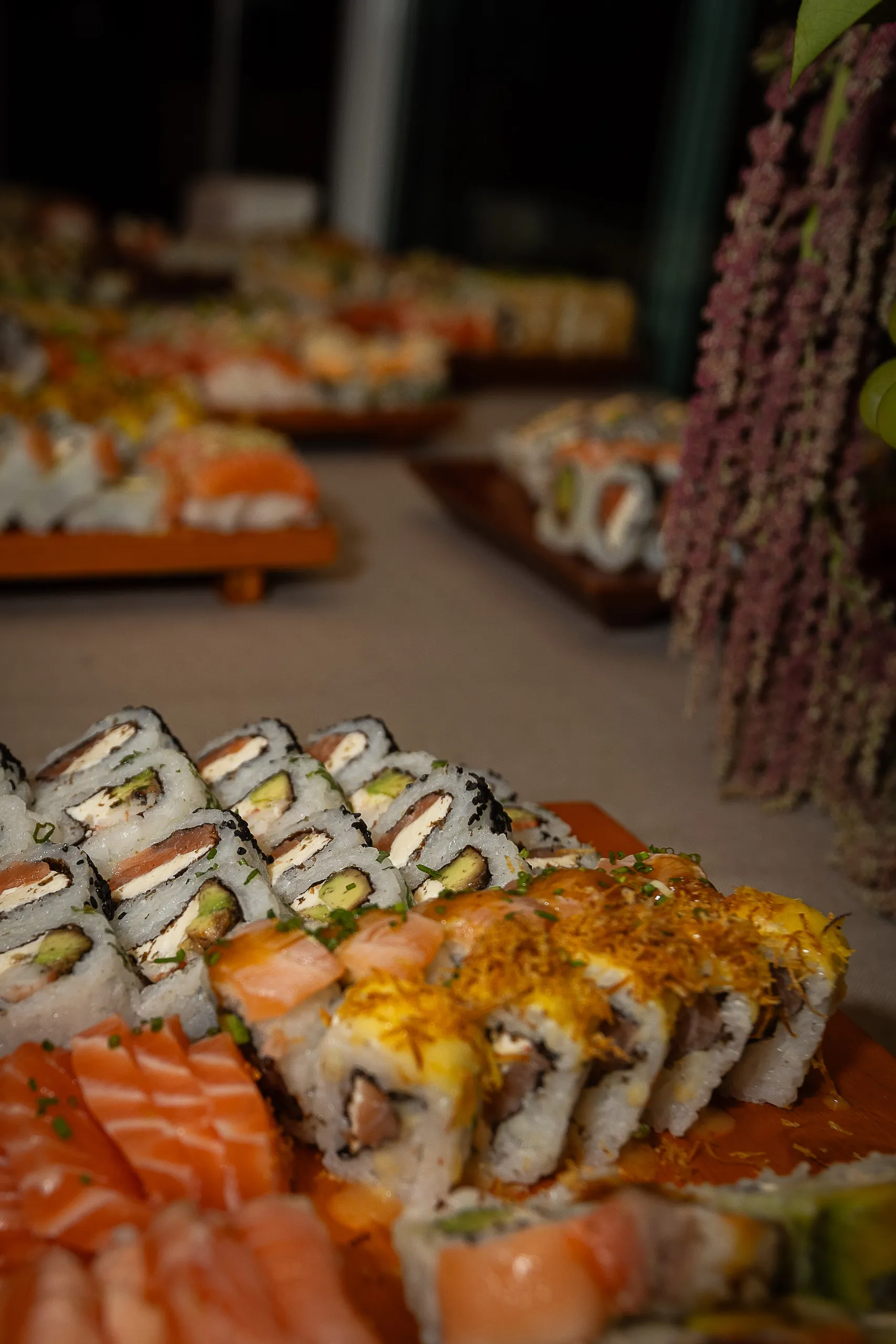 Bandejas de sushi servidas bajo una instalación de flores colgantes