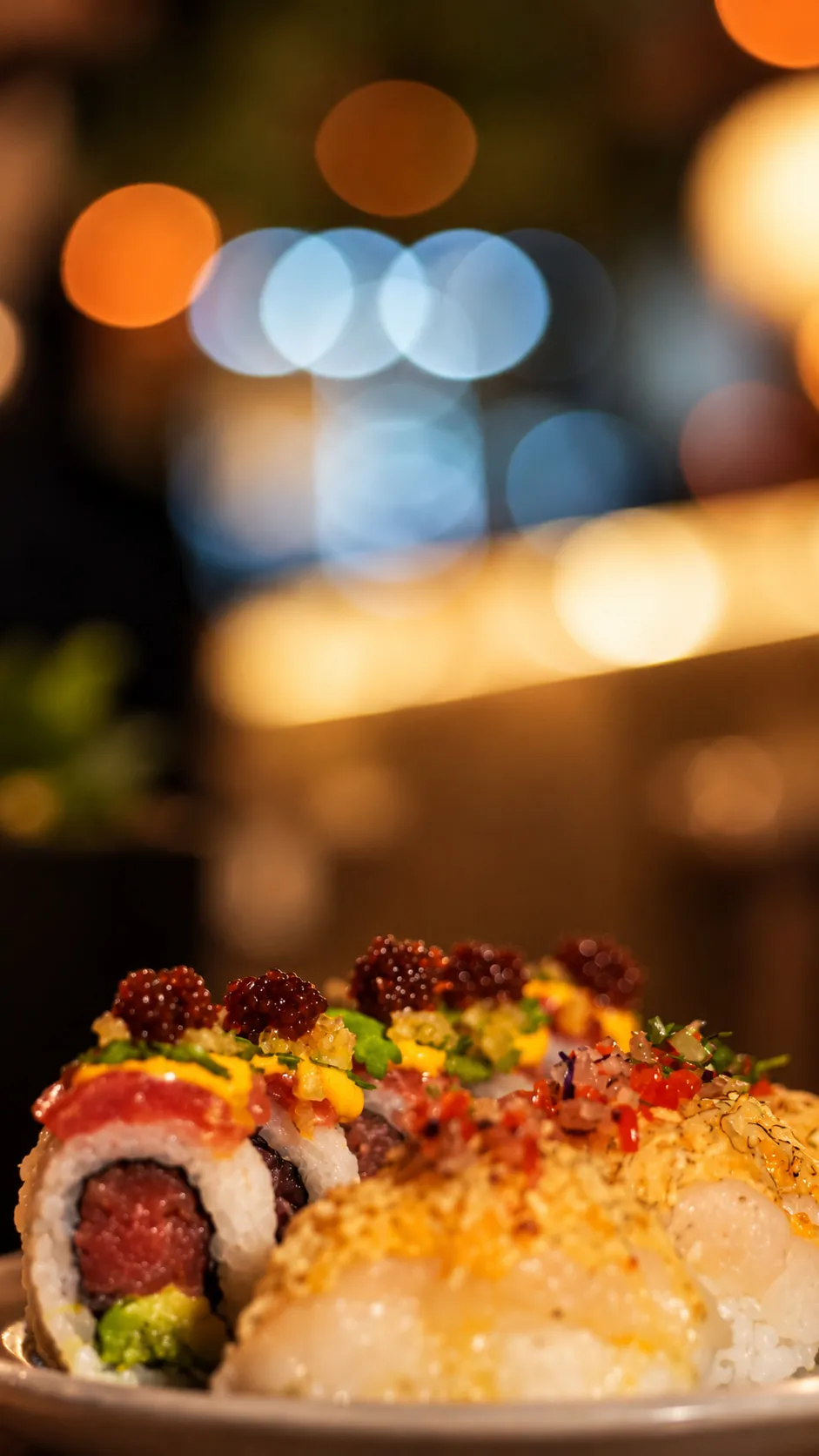 Piezas de sushi en primer plano, con las luces de la fiesta desenfocadas atrás