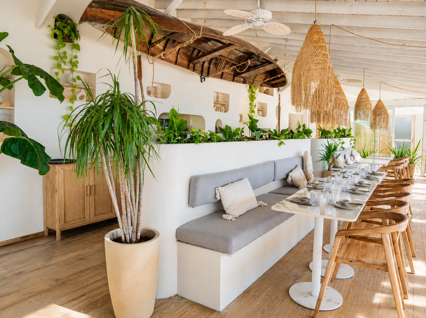 Banco corrido con mesas y plantas en el salón