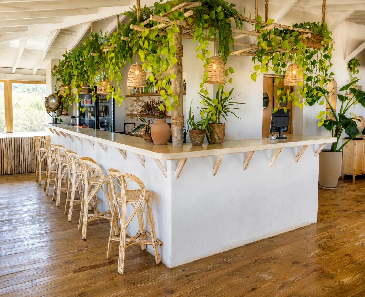 Barra blanca con enredaderas y banquetas de ratán